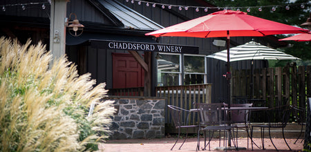 View of Chaddsford's patio includes shaded tables, greenery and a stone bar. 