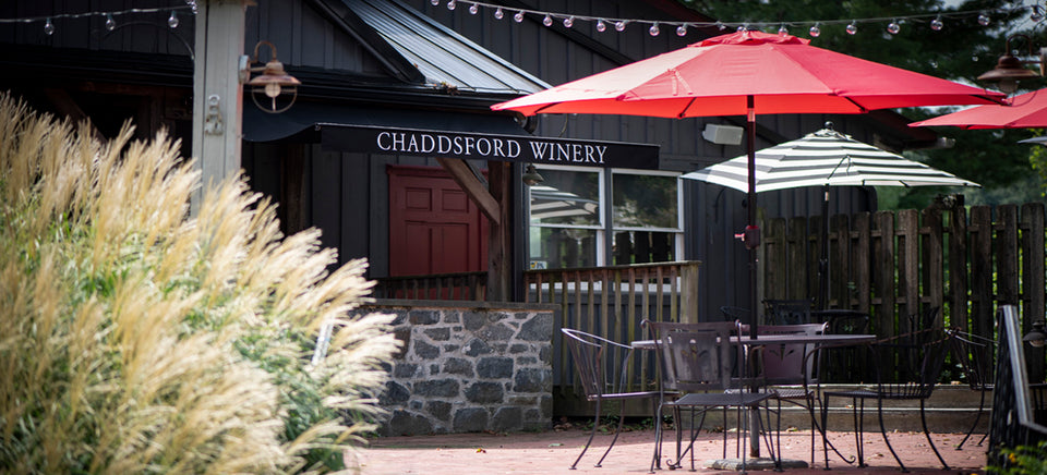 View of Chaddsford's patio includes shaded tables, greenery and a stone bar. 