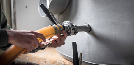 Our cellar associate is pictured adjusting a hose connected to a stainless steel tank. 