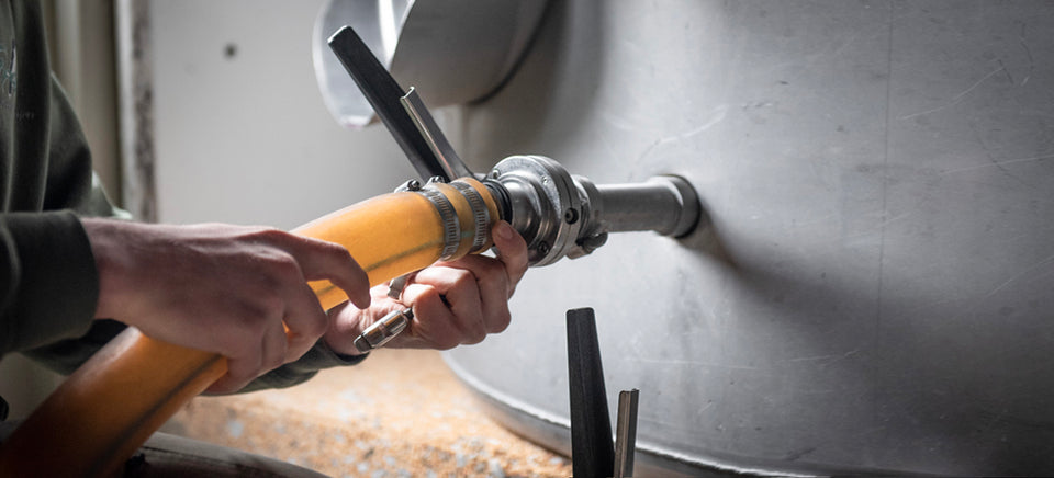 Our cellar associate is pictured adjusting a hose connected to a stainless steel tank. 